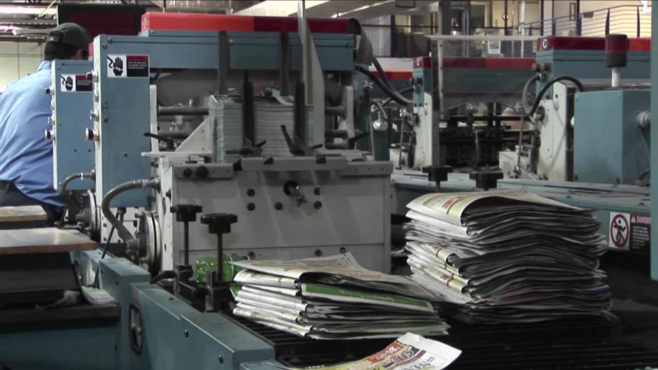 Workers man the printing presses in a newspaper factory