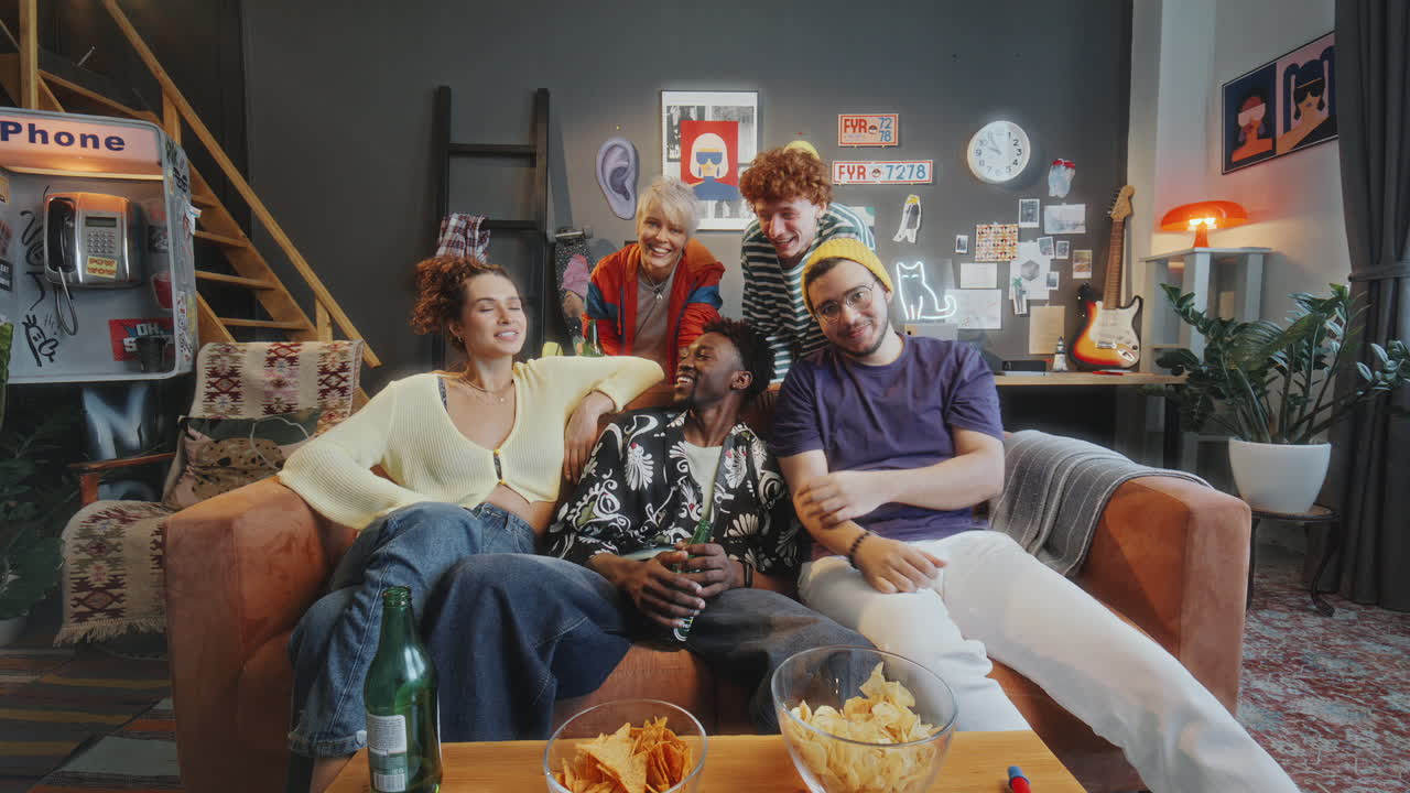 Group of Young Friends Watching Comedy Show on TV and Laughing