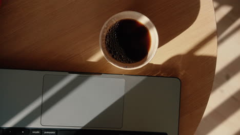 top down shot of hot coffee in a mug next to laptop in home office