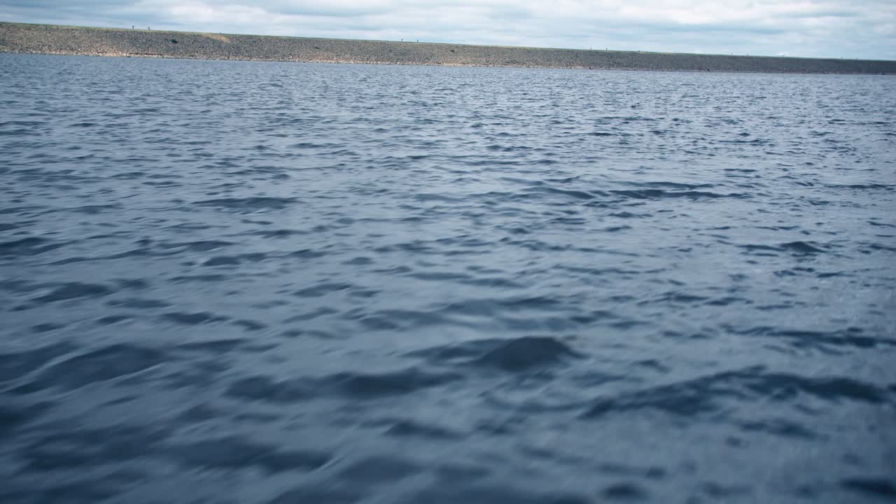 Peaceful rippling blue water surface glistening under soft natural light — perfect serene ocean or lake background footage