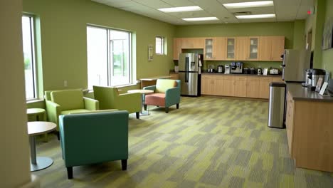 a modern break room with cozy seating, sleek appliances, and vibrant green walls, ideal for relaxation and refreshments in an office environment