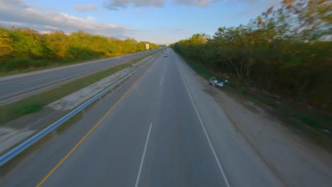 drone speed flight over highway with traffic following car on road during sunny day in rural area of dominican republic