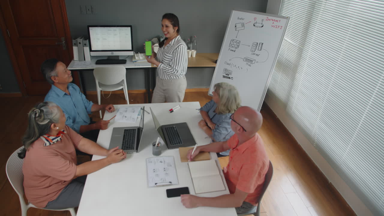 Instructor Explaining App Work on Phone with Green Screen to Seniors