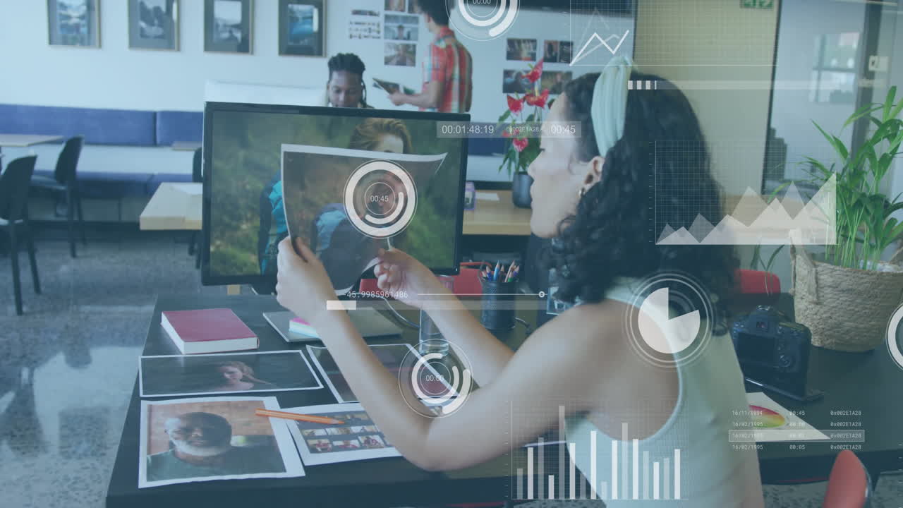 Creative team reviewing photographs with data processing animation overlay in office