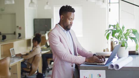 African-american-businessman-using-laptop-with-colleagues-in-creative-office