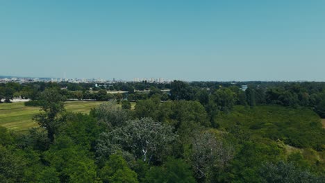 green fields and trees open toward blue lake and city skyline in zagreb
