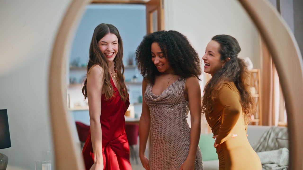 Trois femmes multiethniques posant devant un miroir, vêtues de robes luxueuses.