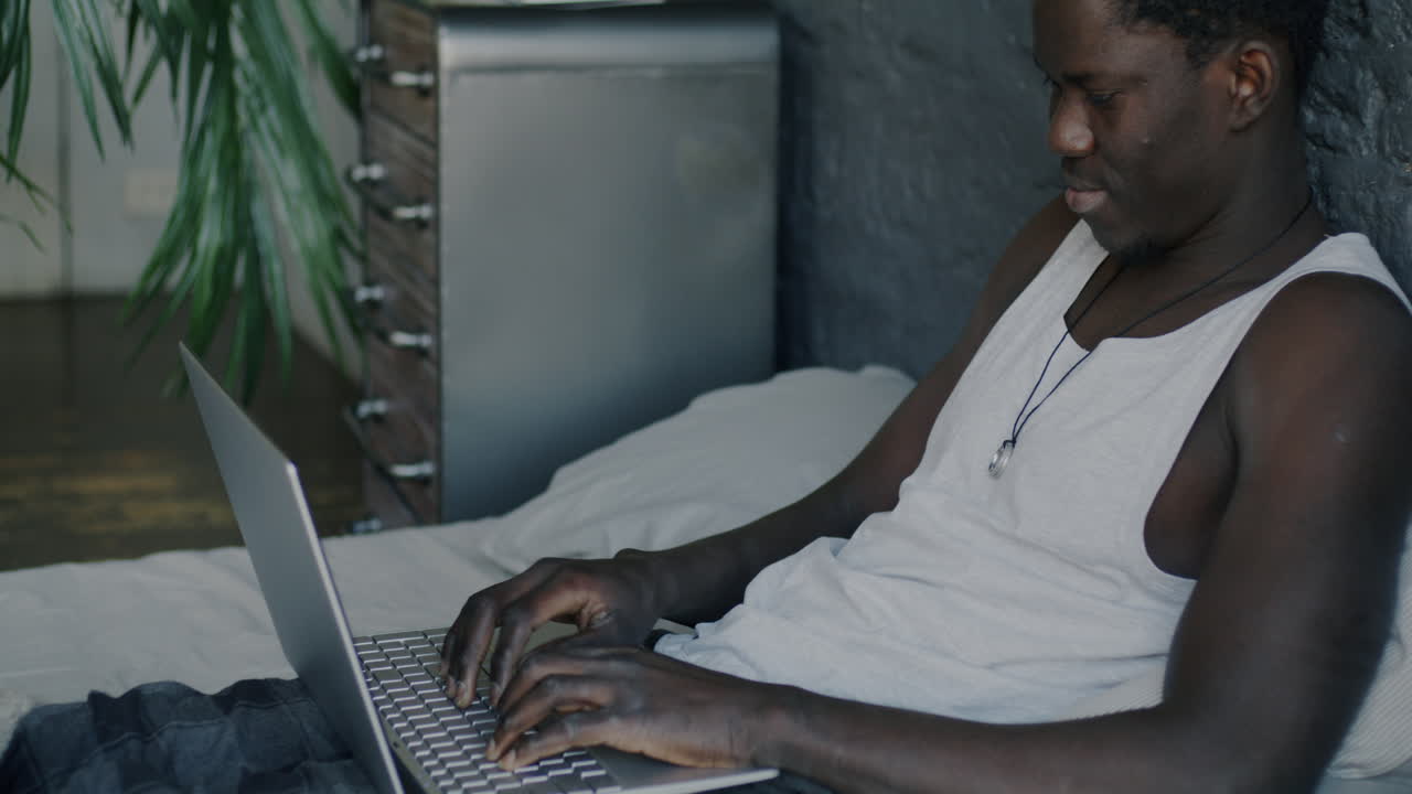 Young man working on laptop in his bedroom