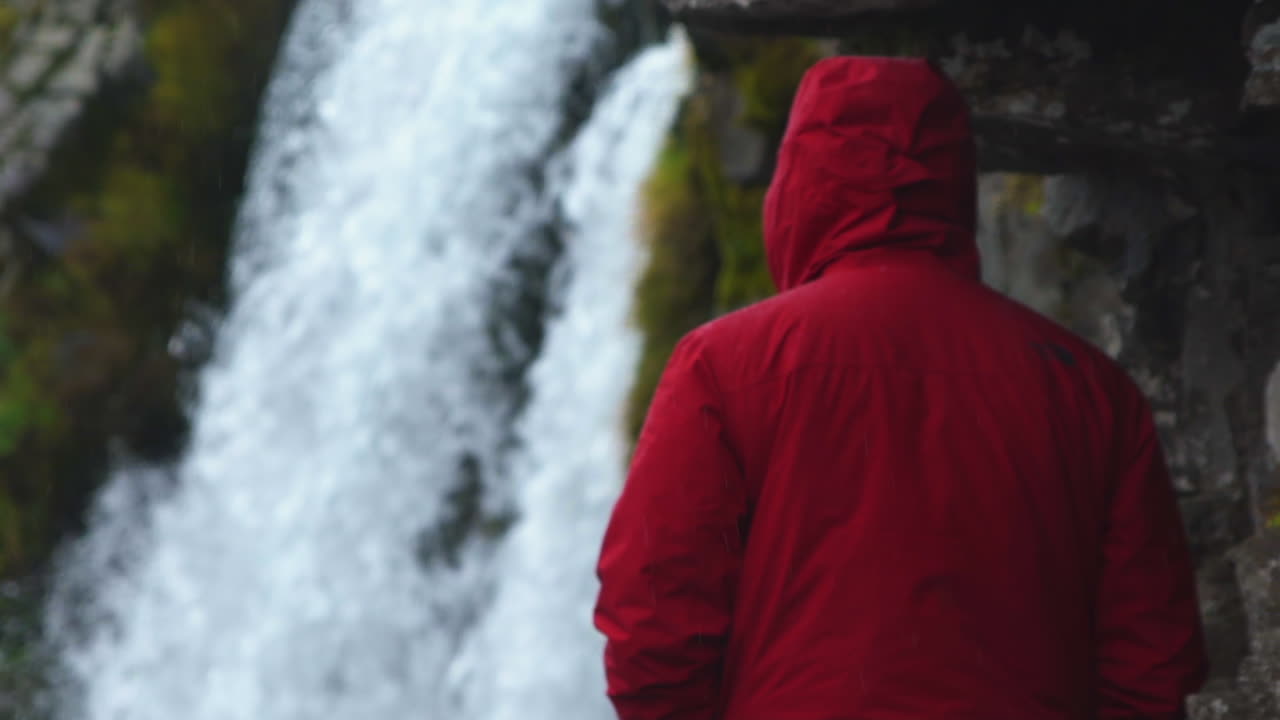 cerrar por detrás del hombre viendo la cascada en cámara lenta