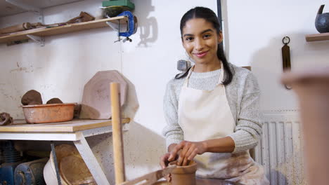 portrait of young african american woman working at pottery wheel in ceramics studio