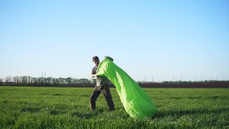 Ein-Mann-Versucht,-Den-Wind-Einzufangen,-Um-Ein-Aufblasbares-Bett-Daraus-Zu-Machen.-Grüne-Farbe.-Schöne-Wiese