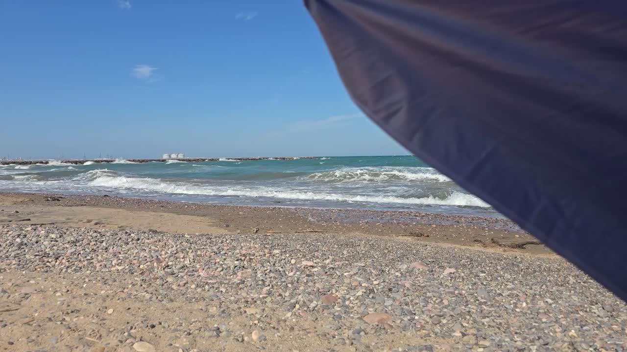 Windy beach with umbrella and waves crashing on the shore