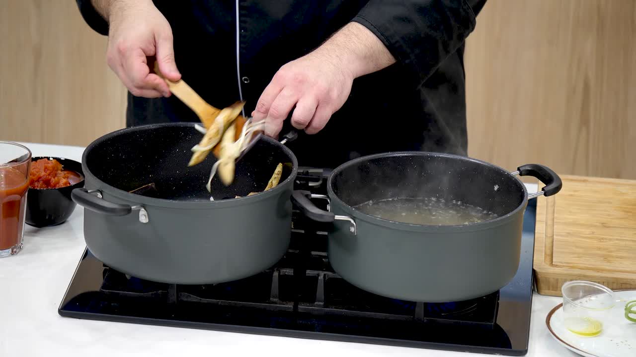 An experienced chef prepares a delicious pasta dish, stirring ingredients in two pots on a stovetop. Fresh ingredients and cooking techniques are highlighted during the process.