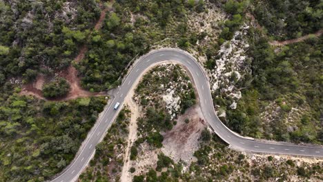 Toma-Aérea-De-Arriba-Hacia-Abajo-De-Un-Automóvil-Conduciendo-Por-Una-Carretera-Con-Curvas-En-Esporles-Durante-El-Día-Soleado,-Mallorca