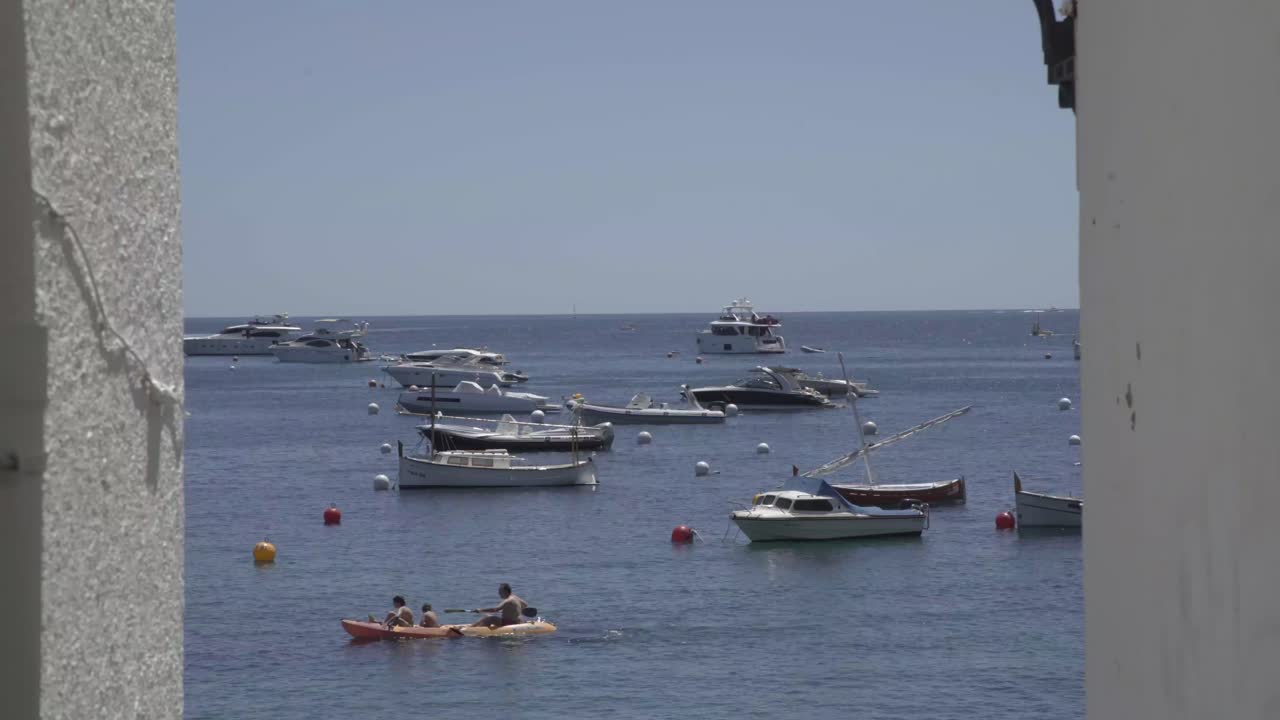 Static boats in the ocean, coast hall in foreground, static shot