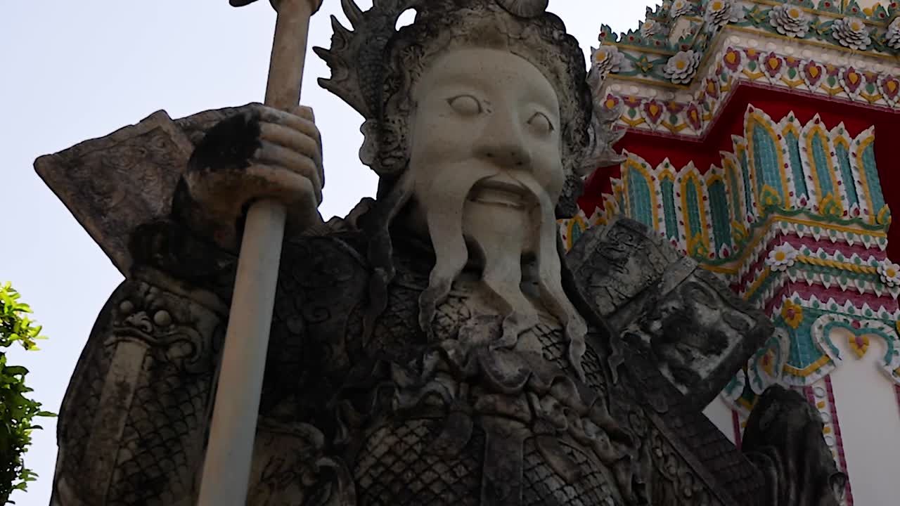 Close-up of a detailed guardian statue with a vibrant, intricate temple facade in the background.