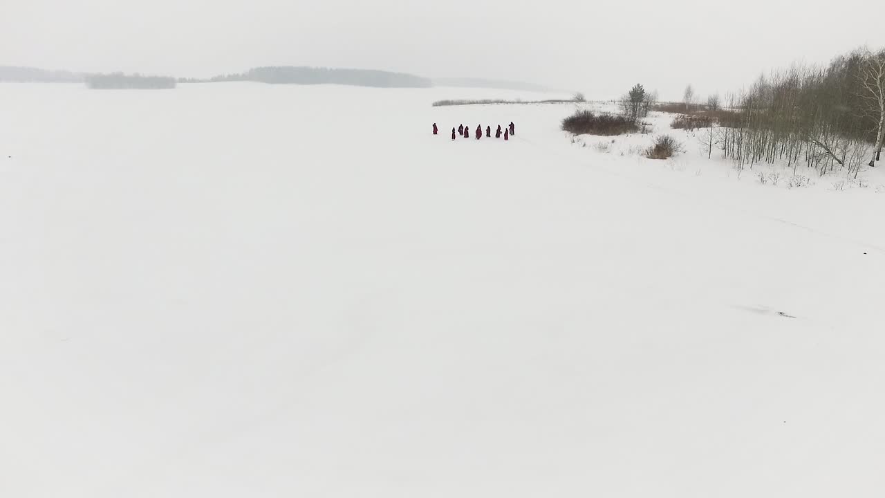 Karlı Bir Manzarada Yürüyen Kırmızı Cübbeli Bir Grup İnsan
