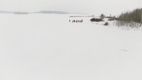 group of people in red robes walking on a snowy landscape