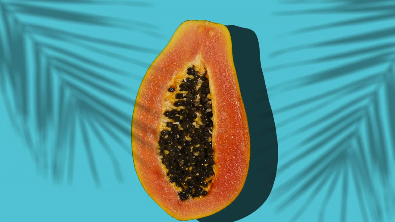 la papaya de frutas tropicales gira sobre un fondo soleado de colores con sombras de una palmera. efecto de movimiento de parada. verano, vitaminas, alimentos, jugo, concepto mínimo