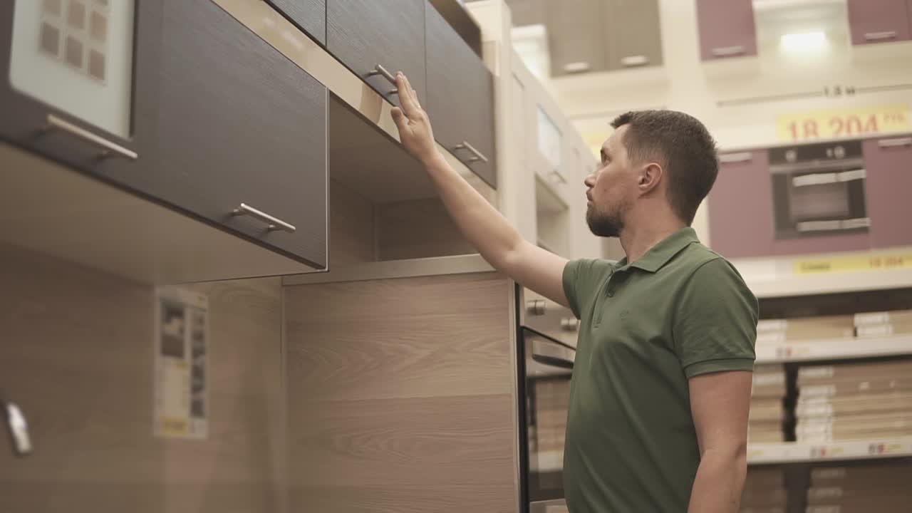 hombre examinando gabinetes de cocina en una sala de exposiciones