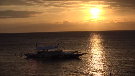 Puesta-De-Sol-Con-La-Luz-Del-Sol-Reflejada-En-La-Superficie-Del-Océano-Y-El-Tradicional-Barco-Banka-Filipino-En-Primer-Plano