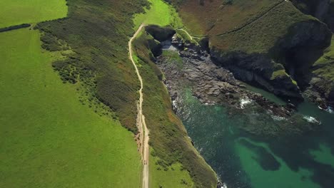 Paseo-Costero-Cerca-Del-Puerto-Isaac-Rodeado-Por-La-Exuberante-Hierba-Verde-Y-El-Agua-Azul-Turquesa-En-Verano-En-Cornwall,-Inglaterra,-Reino-Unido