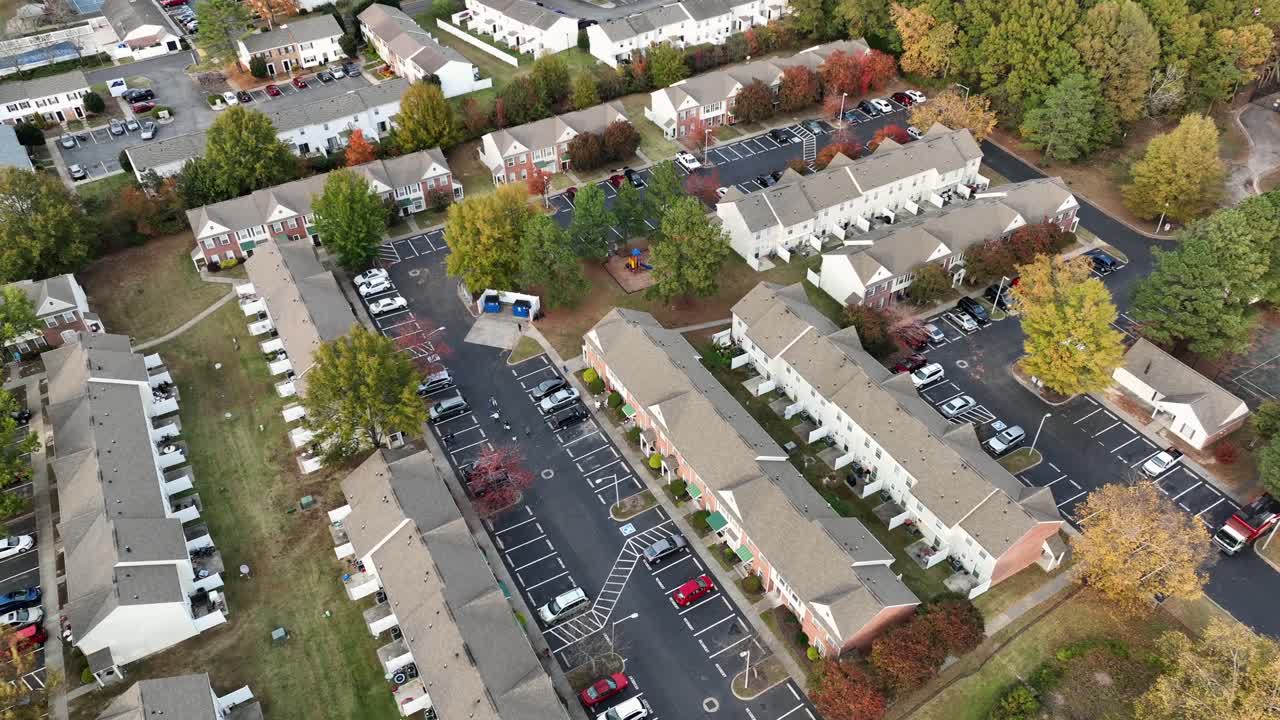 American neighborhood with townhouses and apartment buildings with parking cars in residential area. Colored trees on sunny day in autumn season