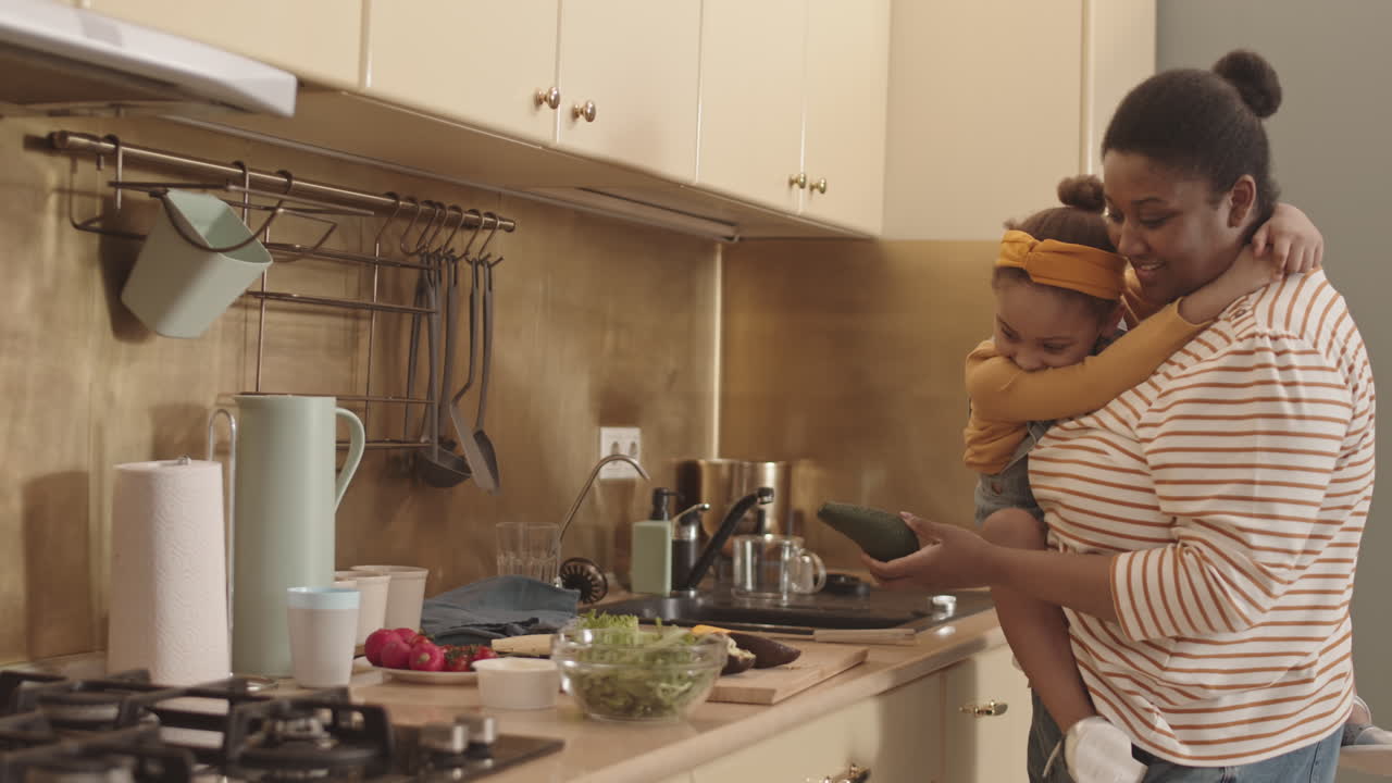 Donna africana che cucina il pranzo con la sua figlioletta
