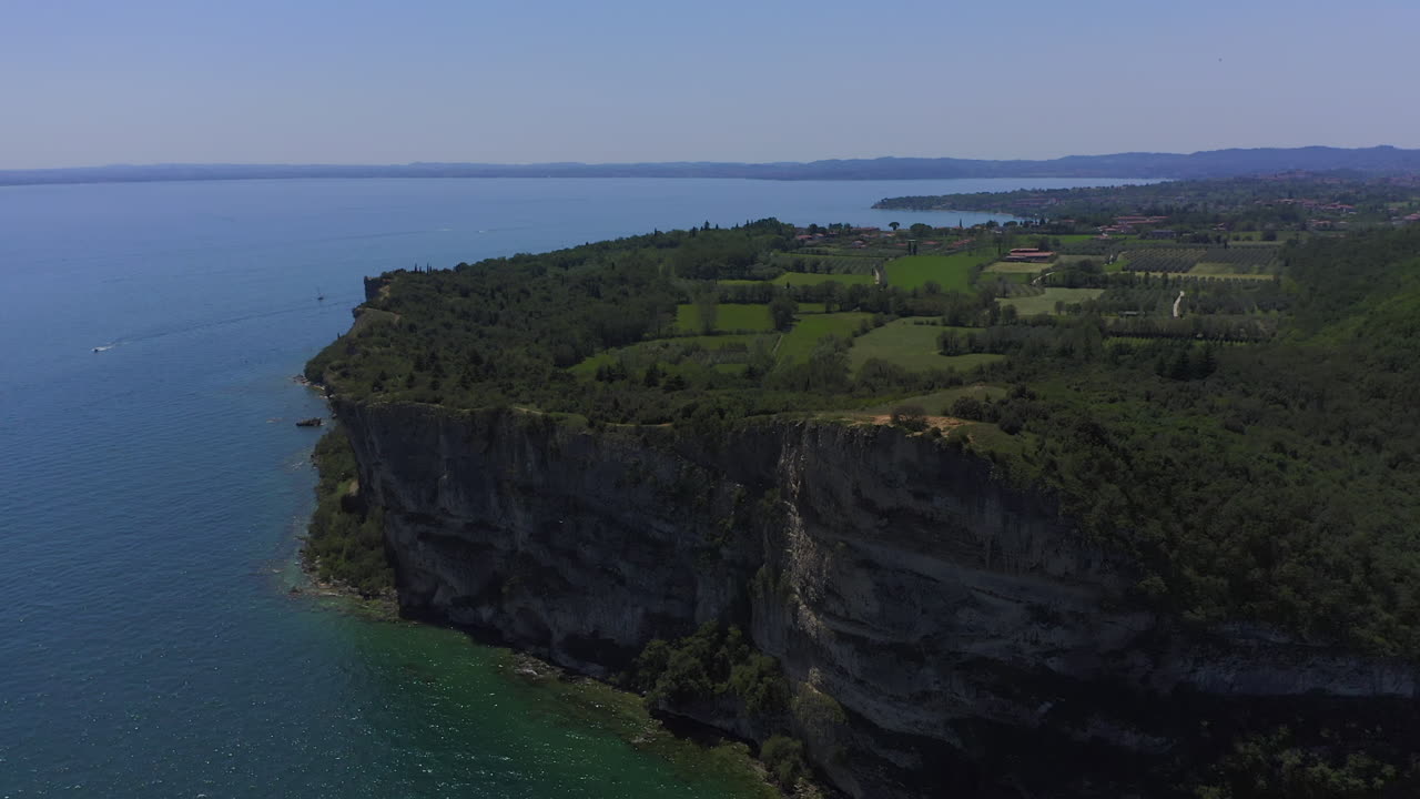 toma aérea acercándose y sobrevolando los acantilados de manerba en el lago di garda en un día soleado