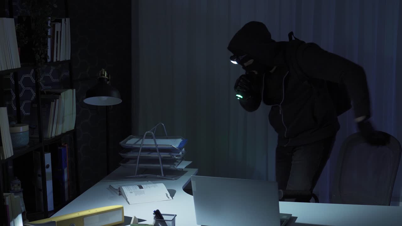 hombre con máscara en la cara comete un robo en la oficina.