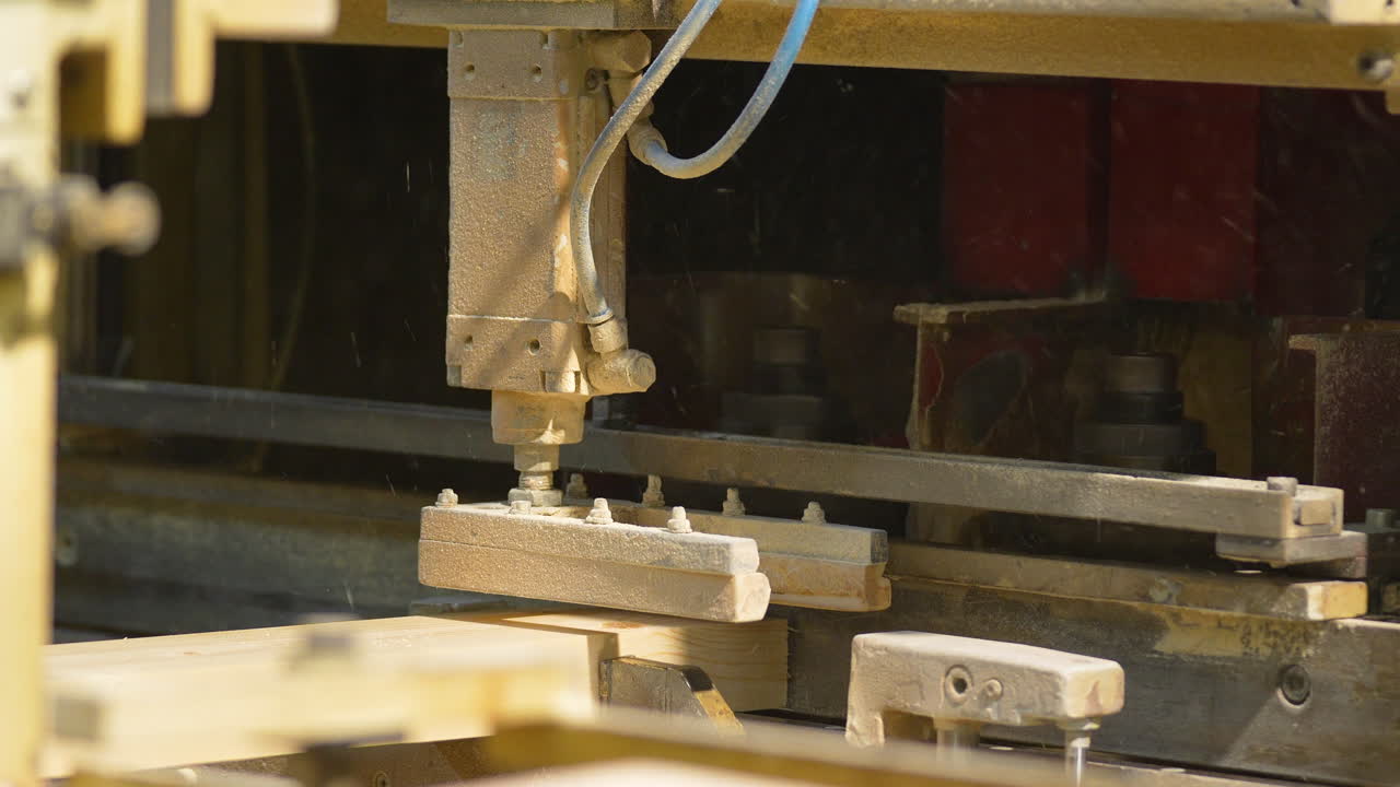 Primo piano di una macchina industriale automatizzata che lavora assi di legno in una segheria. Perfetto per contenuti sulla produzione industriale, la produzione di legname e la tecnologia della lavorazione del legno.