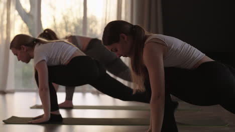 jóvenes deportivos caucásicos practicando una lección de yoga con un instructor. grupo de mujeres caucásicas ejercitando un estilo de vida saludable en un gimnasio. actividad deportiva clase de gimnasia. cámara lenta.