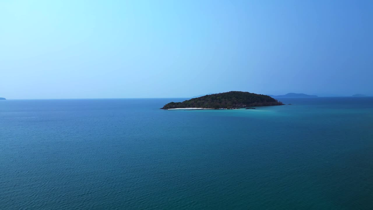 Koh Kham Island with its green tropical vegetation surrounded by crystal clear turquoise waters, Thailand. Marvelous aerial view flight fly push forward drone
