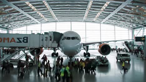 a bustling airport scene showcasing the arrival of passengers as they deboard from a commercial airplane at a modern terminal equipped with jet bridges and airport staff