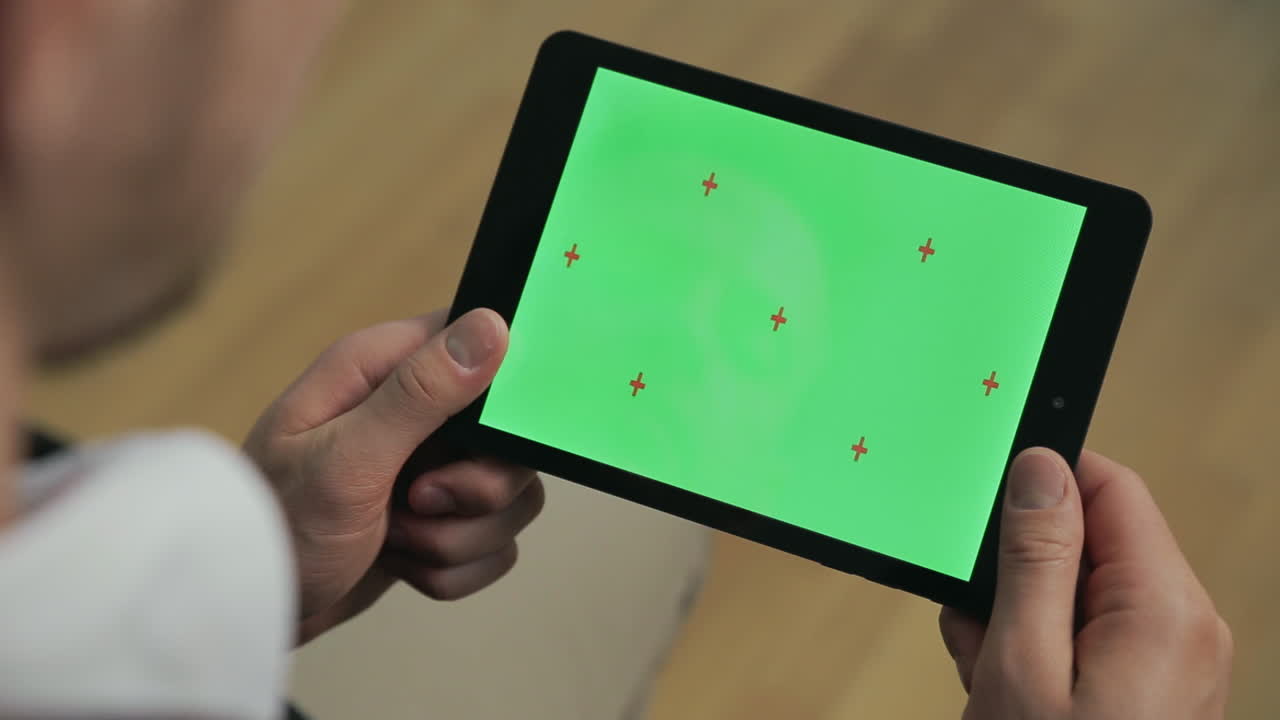 Ung mand holder tablet-pc med grøn skærm. Mandehænder rører tabletskærmen.