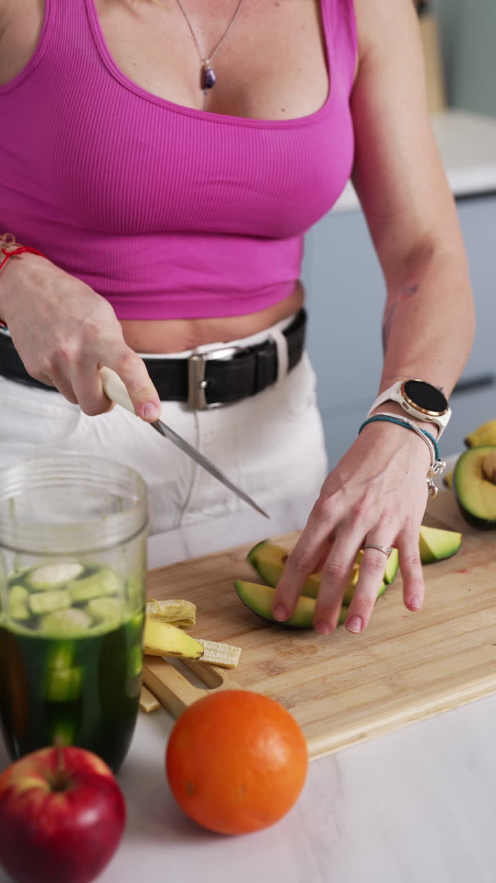 Vertical - Tattooed Woman In Kitchen Cutting Fresh Avocado For Smoothie. medium shot