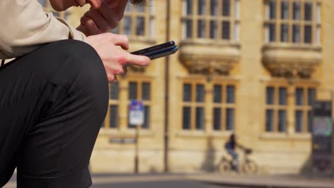 Close-Up-Shot-of-Man-Looking-at-Phone-On-Old-Street-In-Oxford-01