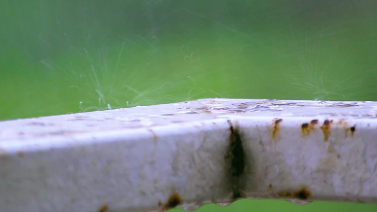 Closeup of rusty metal during rain. Water drops falling and evaporating on corroded surface. Ideal for weather, decay or industrial themes. Nature meets infrastructure