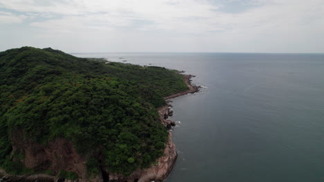 el dron orbita de izquierda a derecha sobre la costa rocosa de punta de mita, revelando montañas y mar en una vista panorámica