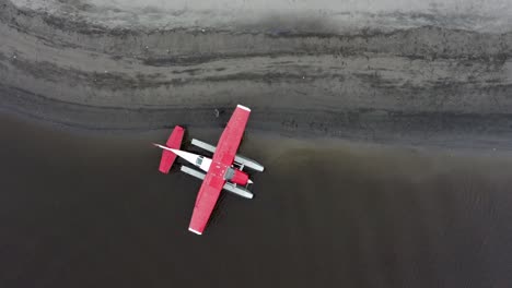 man preparing alaskan floatplane on the shore for flight