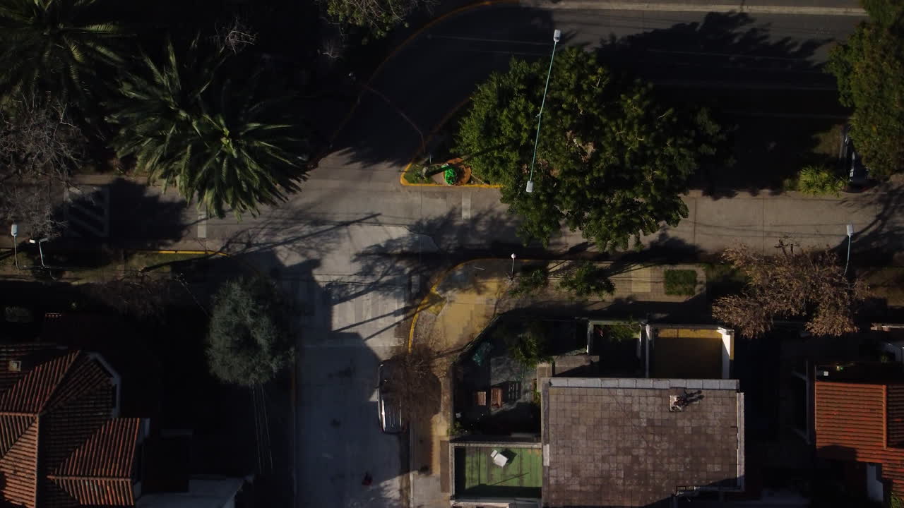 A man walks along an empty roadway, near private houses, along an intersection, shooting from above, rails