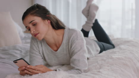 happy woman using smartphone texting browsing social media messages enjoying mobile phone communication lying on bed at home