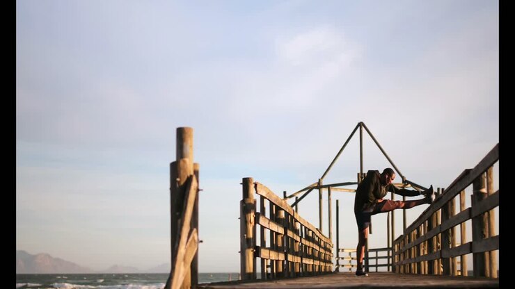 Jogger uomo afroamericano che si allena sul molo in spiaggia 4k