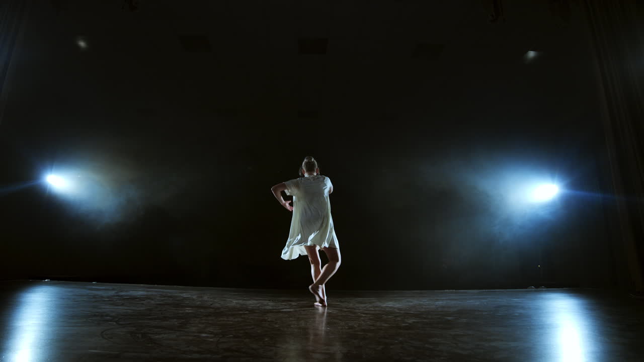 Dynamic scenes from the musical solo performance of a modern ballerina. Dancing on stage in the spotlight in slow motion. Dance musical show. Dramatic scene in the moonlight.