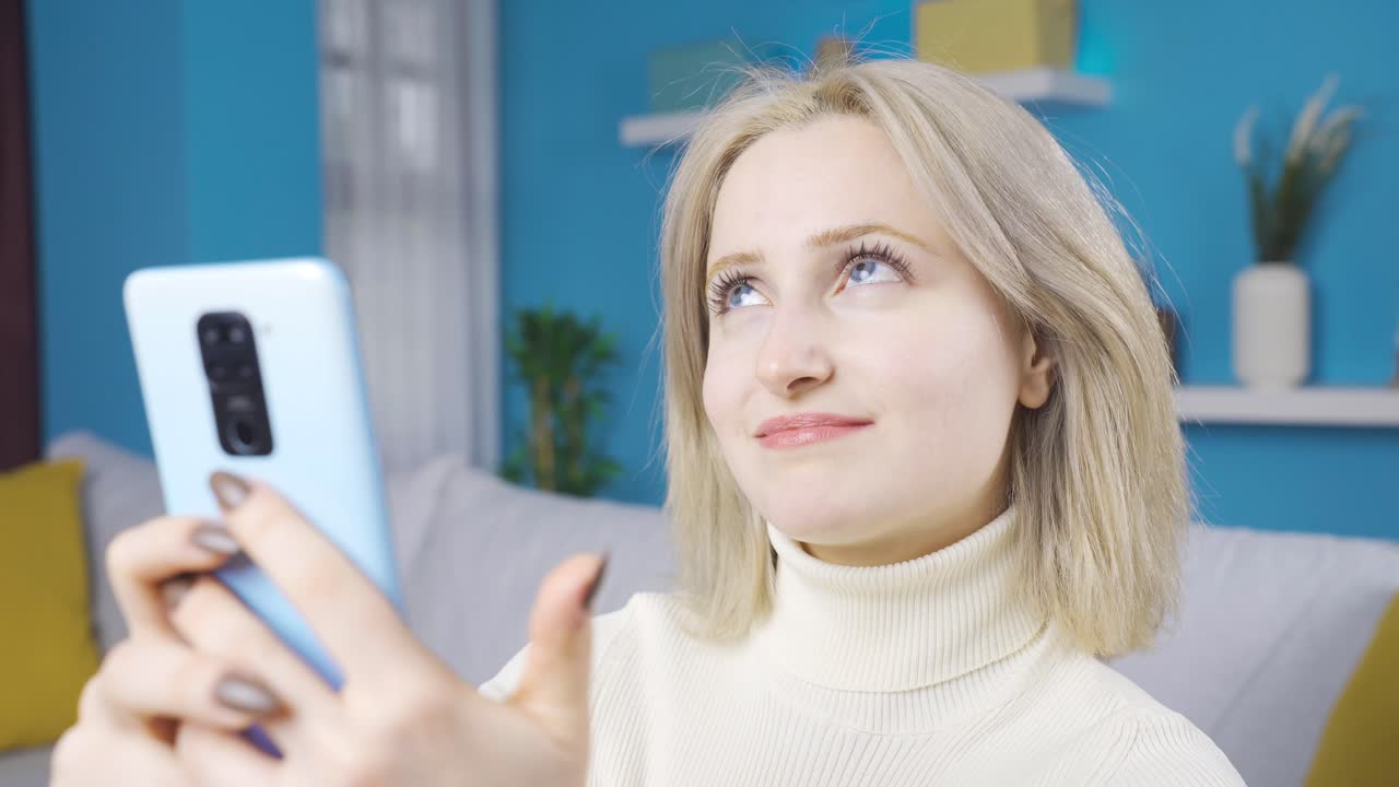 집에서 전화로 문자 메시지를 보내는 아름다운 여성은 행복하고 귀 ⁇ 습니다.