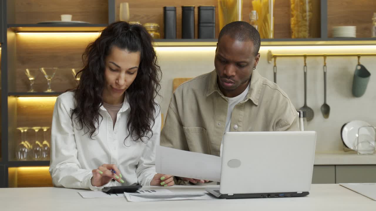 Young couple makes counts sitting near laptop at table
