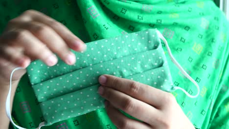 woman holding a green dotted face mask