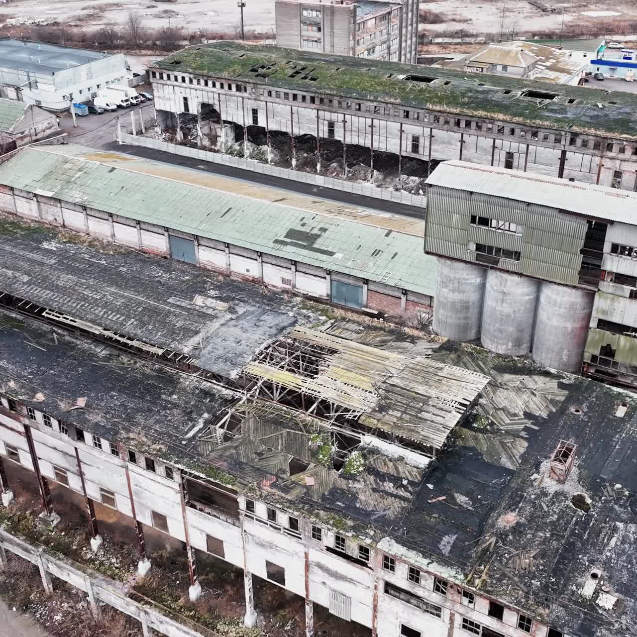 Neglected locality of a past time plant. Abandoned ruins of warehouses with broken walls, windows and roofs. Aerial view