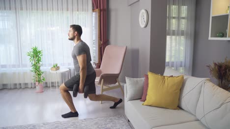 young man exercising at home is training with dumbbells.