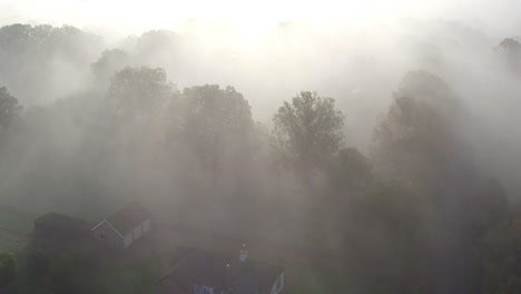 Aerial-view-over-unrecognizable-house-in-a-spooky-setting-in-Dense-fog-and-woodland,-Shot-at-Dering-woods,-Kent,-UK